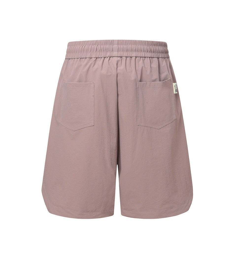 Dusty mauve knee-length shorts shown from the back, with an elastic waistband and two patch pockets.
