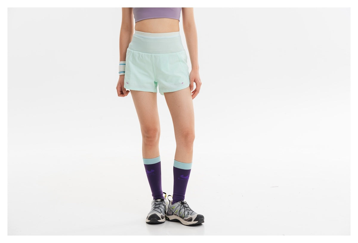 Front view of a model wearing mint athletic shorts with a wide waistband and purple knee-high socks.