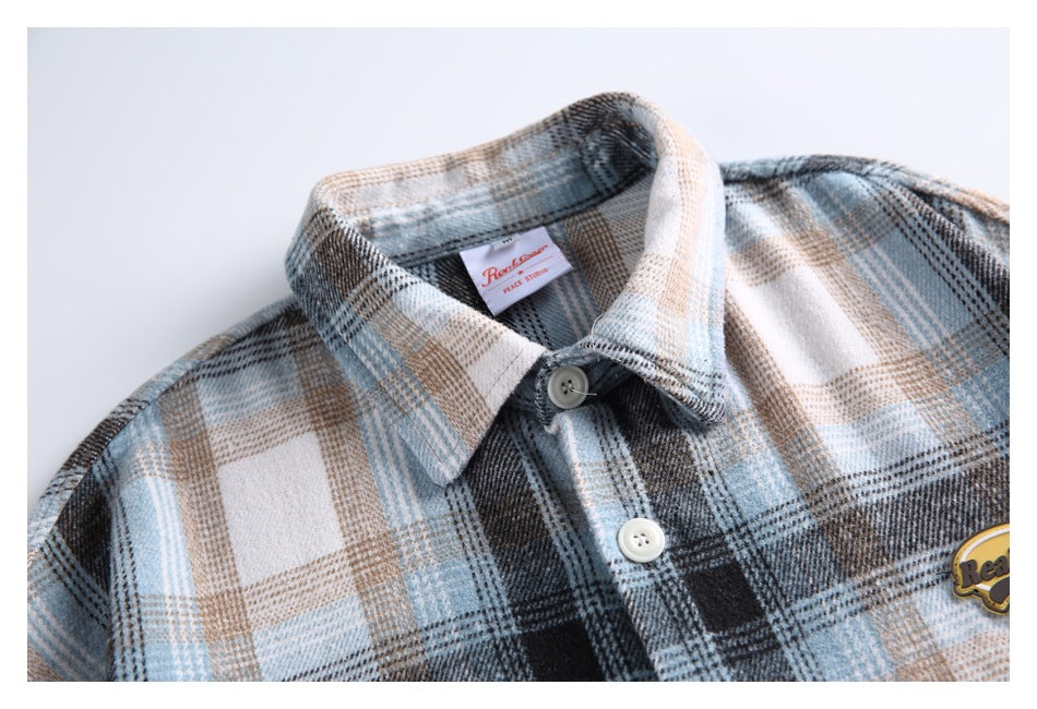 Close-up of the shirt collar, white buttons, blue-gray plaid and sewn neck label.