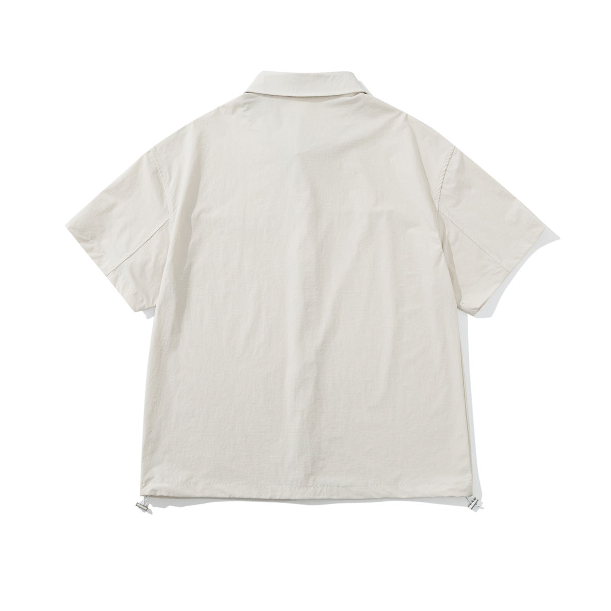 Back view of a cream short-sleeve button-up shirt with a collar and adjustable hem tabs.