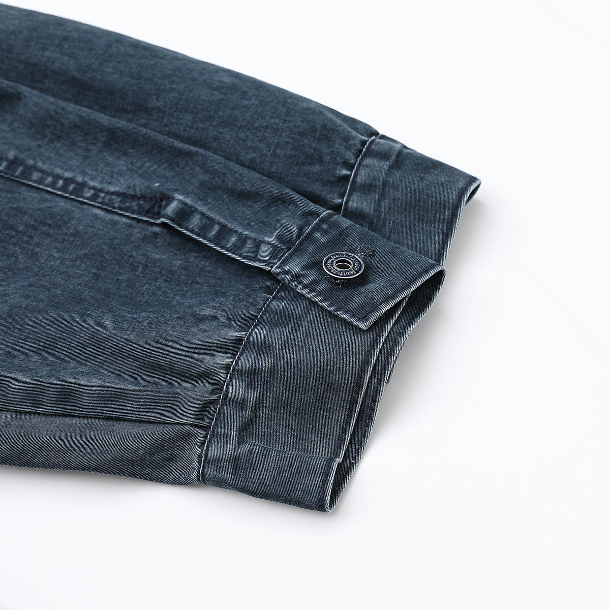 Close-up of a dark blue denim jacket sleeve cuff with a button fastening.