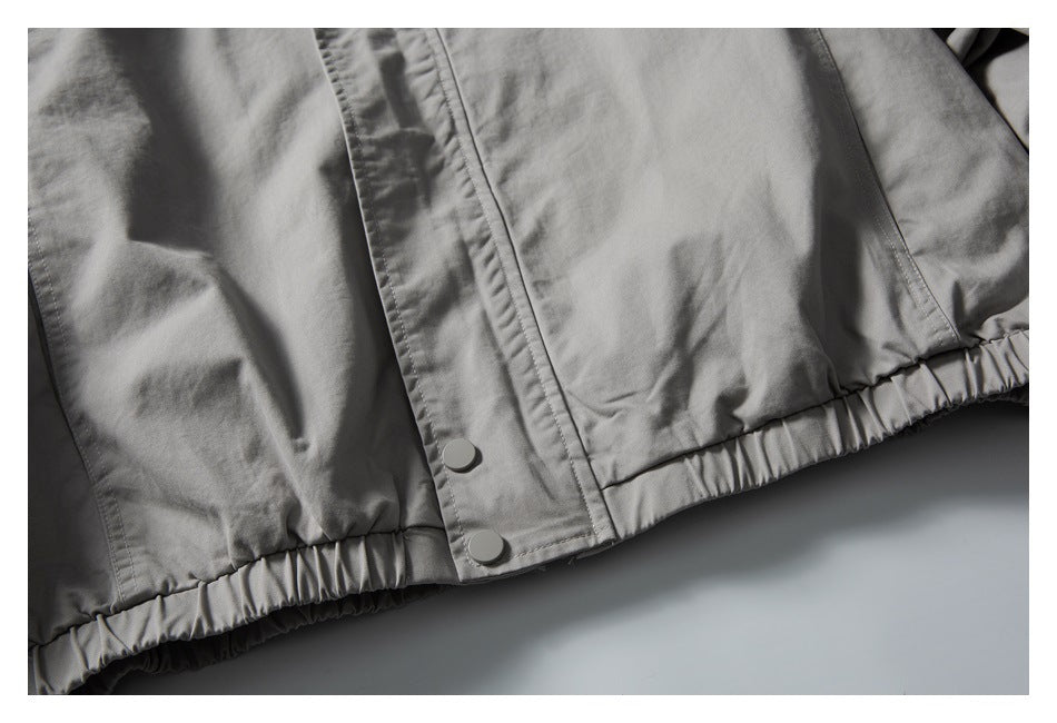 Close-up of the gray jacket’s gathered elastic hem and snap-button front placket.