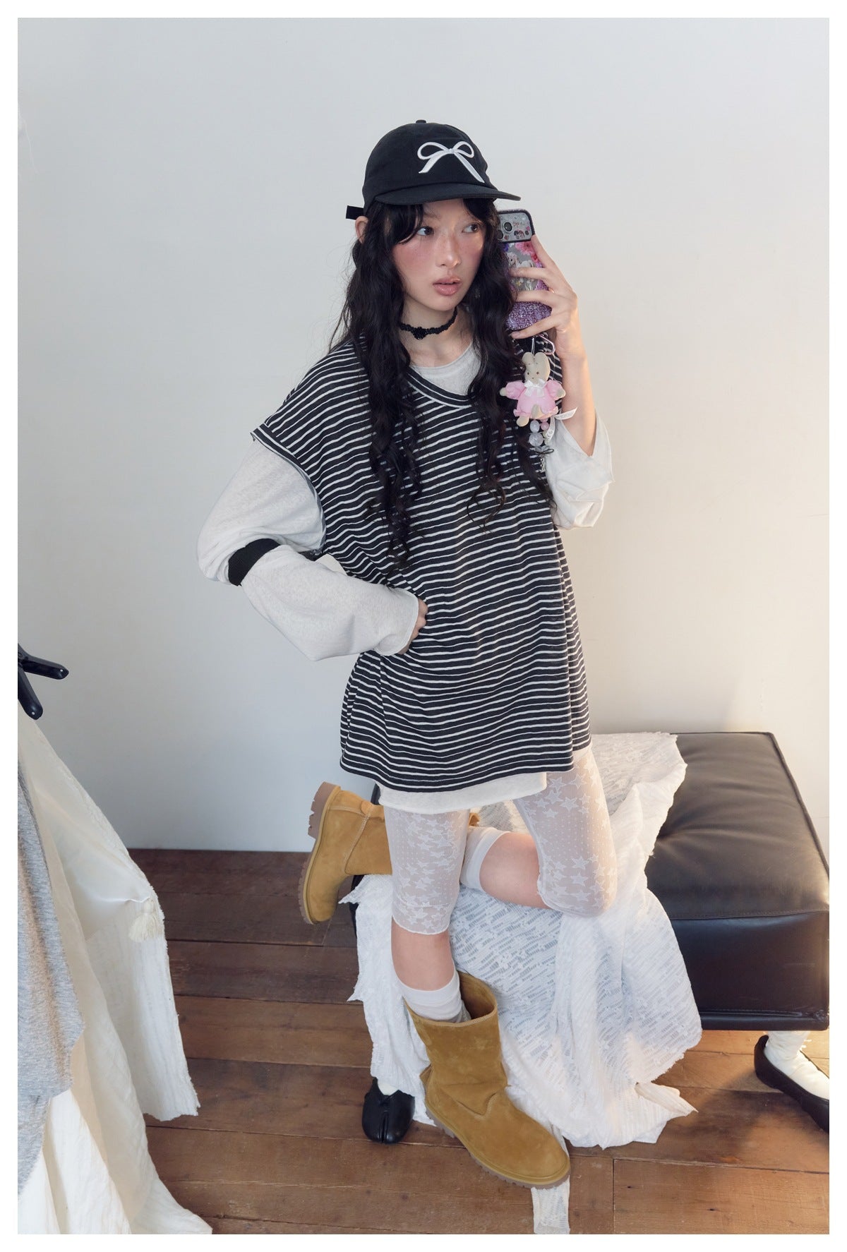 Model wearing a black-and-white striped sleeveless top layered over a light gray long-sleeve shirt.