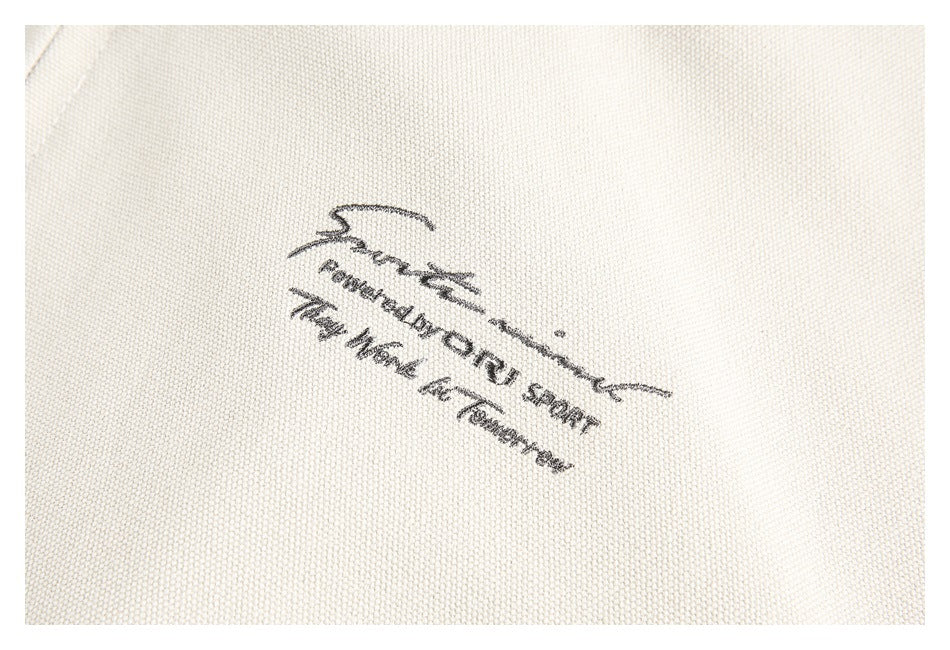 Close-up of black lettering and a script-style graphic printed on cream textured fabric.