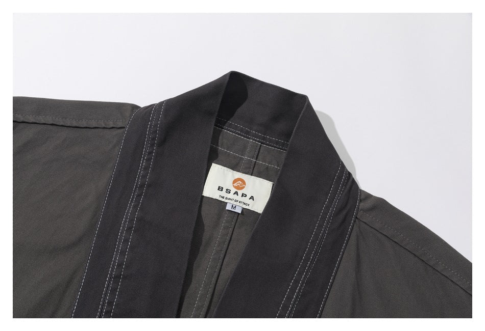 Close-up of a charcoal jacket collar, contrasting stitching, and sewn brand and size label.