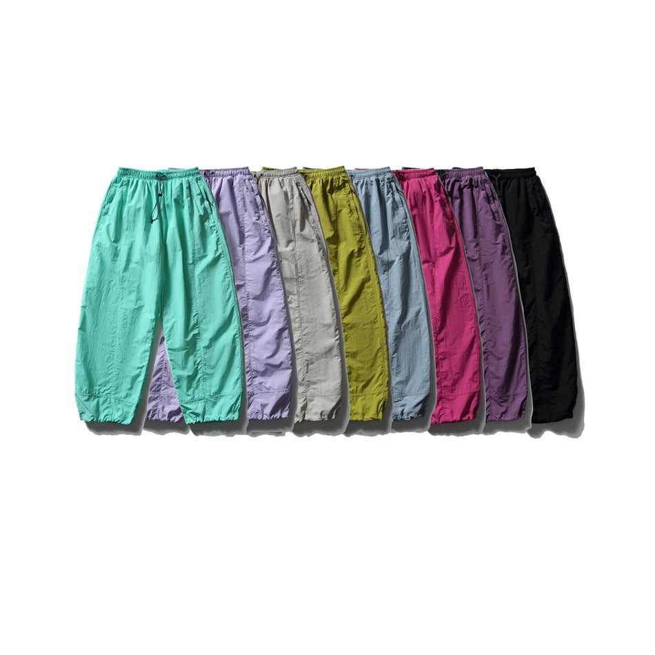 A row of pants in turquoise, lavender, gray, olive, blue-gray, magenta, purple, and black.
