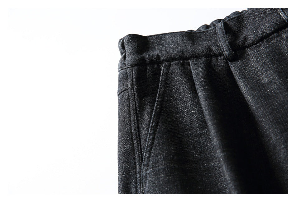 Close-up of charcoal-black trousers showing a slanted side pocket, waistband and belt loop.