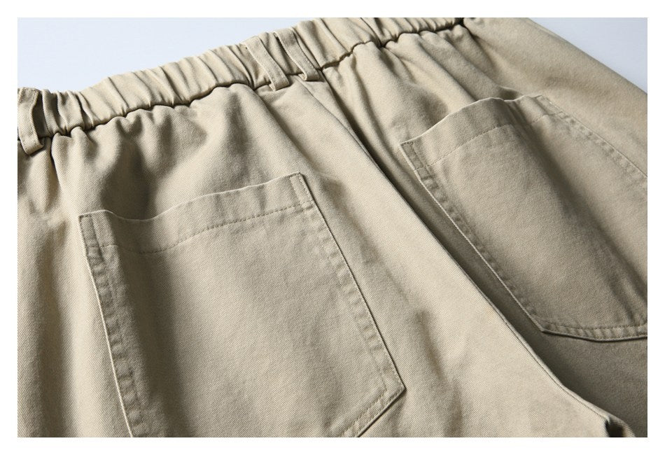 Close-up of the gathered waistband and two patch pockets on the back of beige shorts.