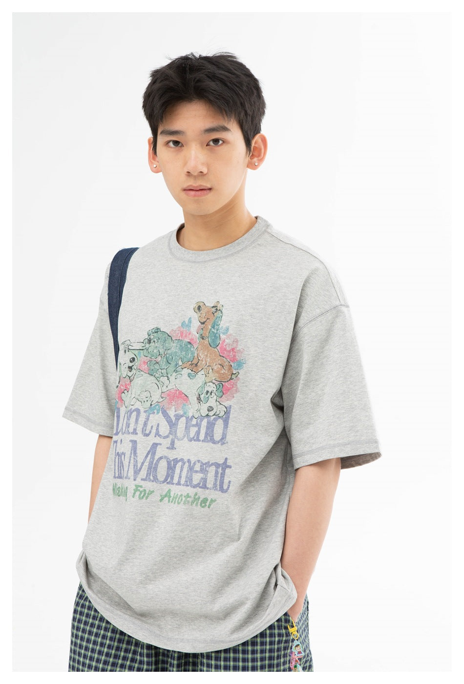 Front view of a model wearing an oversized gray animal-print T-shirt and green plaid shorts.