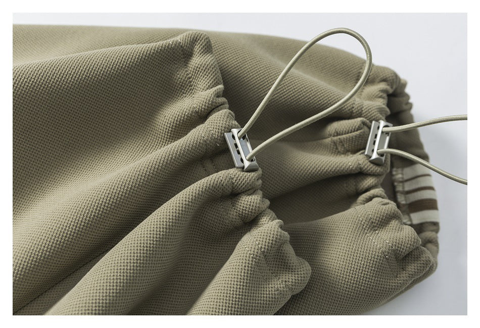 Close-up of olive-gray gathered fabric with cord loops and metal adjusters.