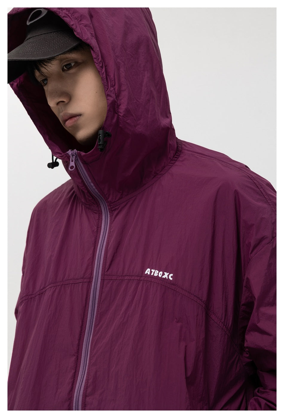 Close-up of the plum jacket's hood, drawcord toggles, front zipper, and small chest logo.