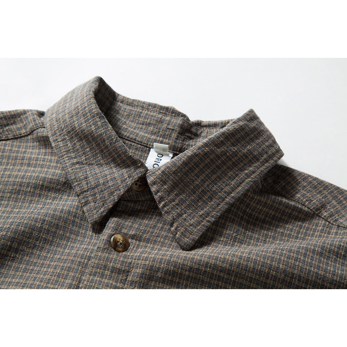 Close-up of a brown and blue small-check shirt collar with dark buttons and a partially visible neck label.