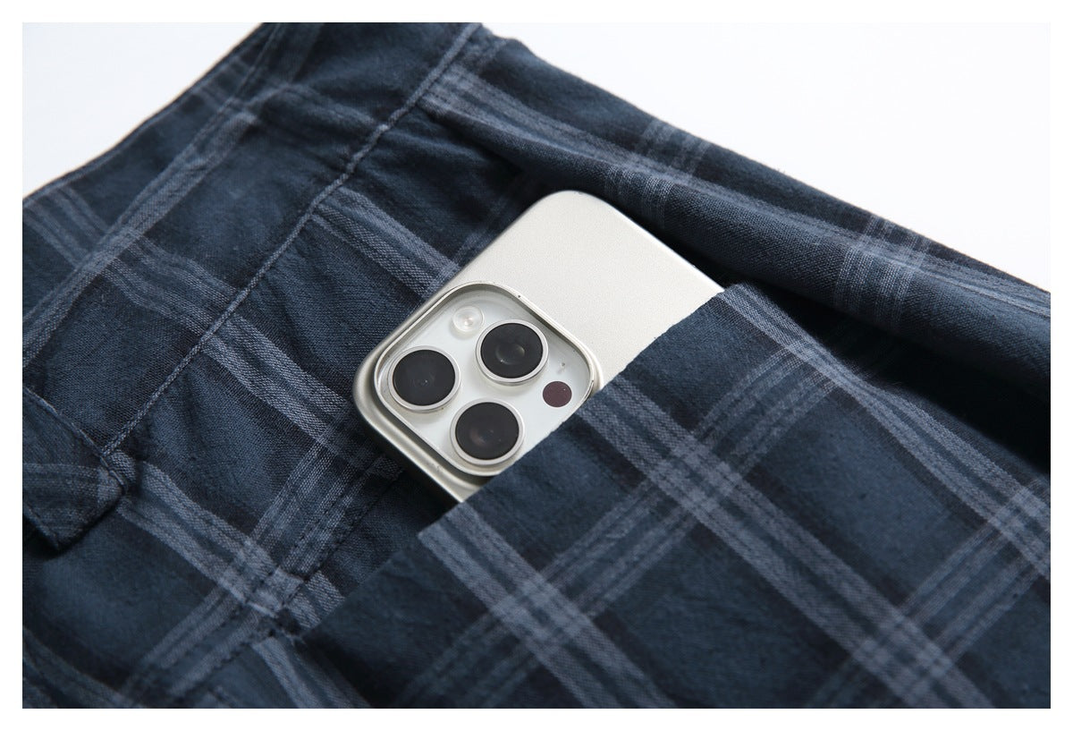 Close-up of dark navy plaid trousers with a silver smartphone partly tucked into a pocket.