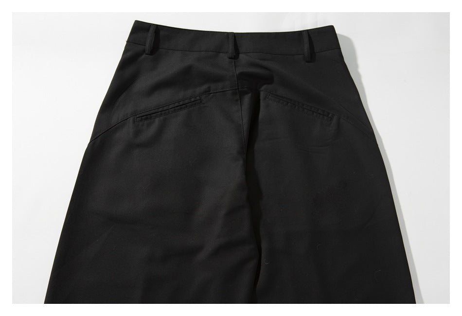Back view of black tailored trousers laid flat, with belt loops and two slanted welt pockets.