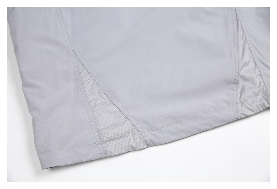 Close-up of a light gray jacket hem with stitched seams and textured side panels.