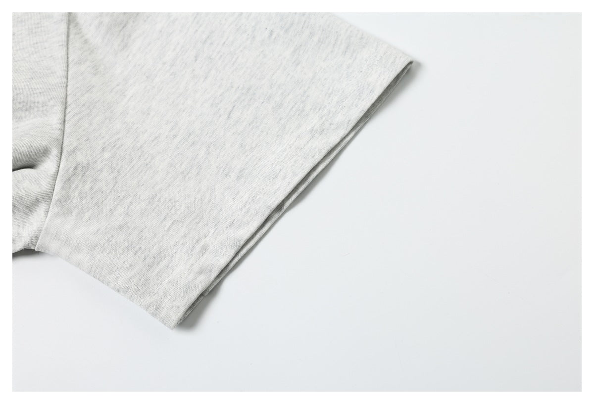 Close-up of the plain light heather gray T-shirt sleeve and stitched hem.