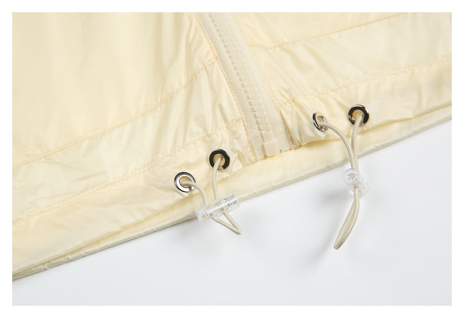 Close-up of a pale yellow garment hem with a zipper and adjustable drawcords threaded through metal eyelets.