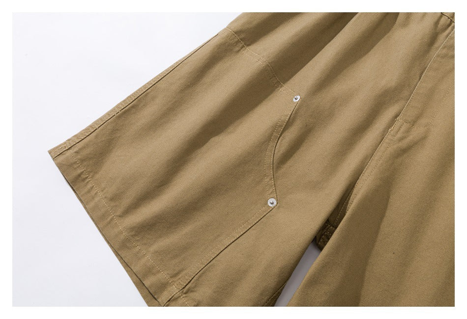 Close-up of a tan shorts leg with a large panel pocket secured by small metal rivets.