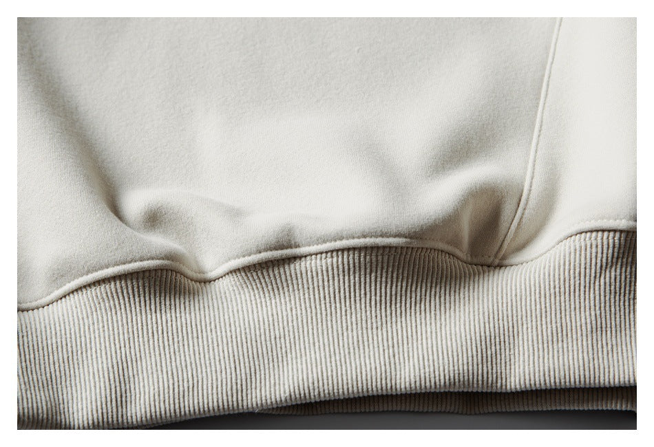 Close-up of the cream sweatshirt's wide ribbed hem and lower body.
