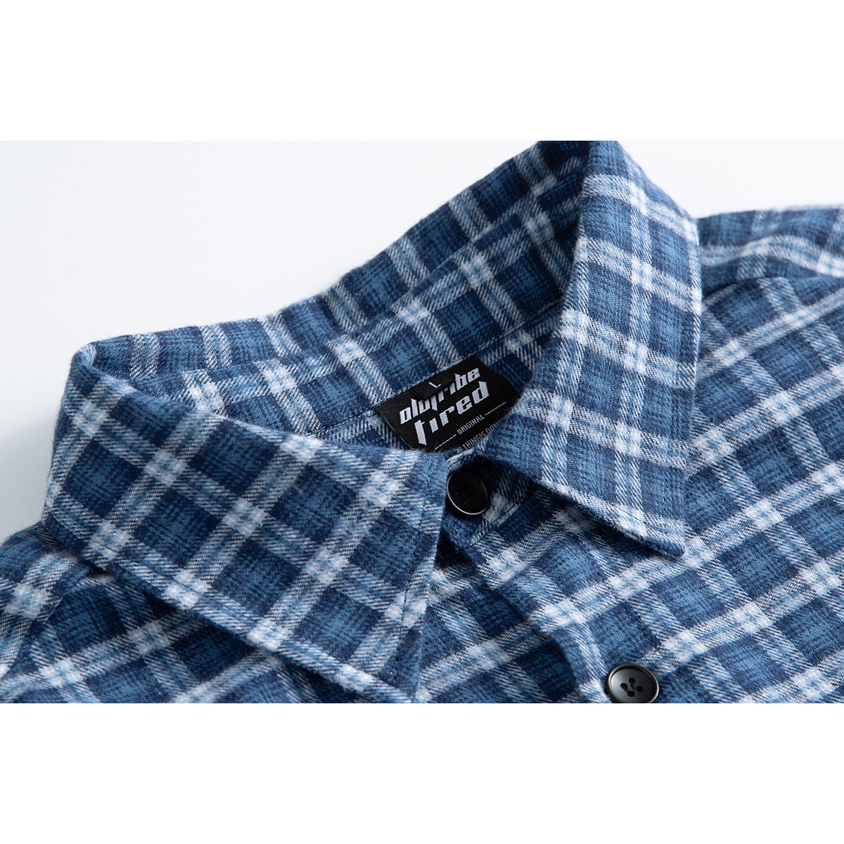 Close-up of a blue-and-white plaid shirt collar, black buttons, and inner neck label.