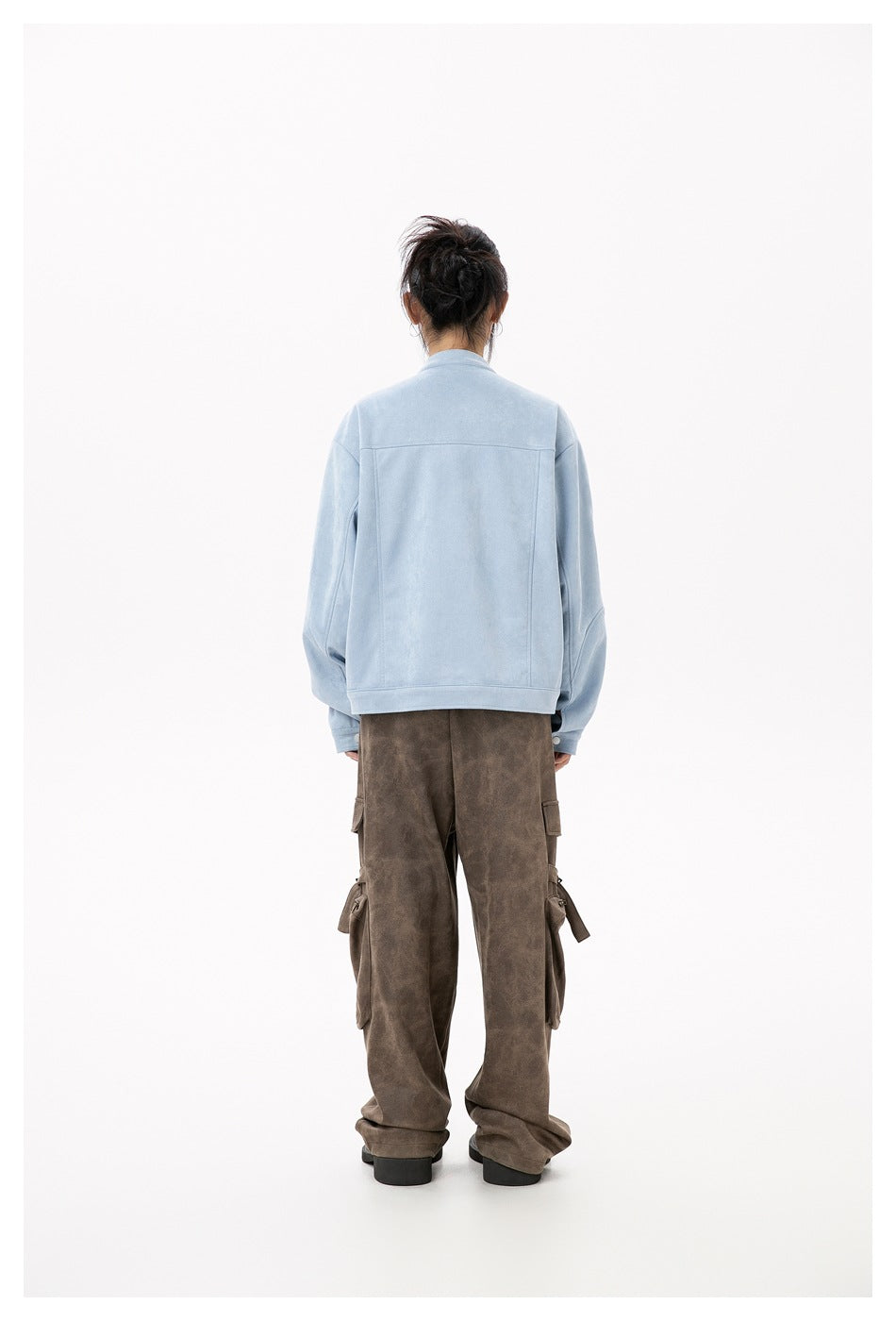 Rear view of a model wearing a light blue jacket with brown cargo pants.