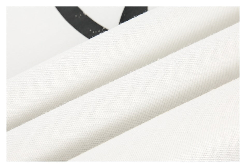 Close-up of folded white ribbed fabric with part of a black graphic in the background.