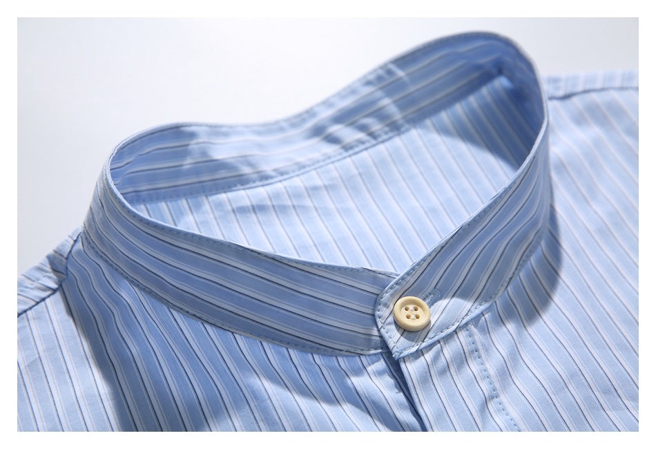 Close-up of the stand collar and cream button on a light blue striped shirt.