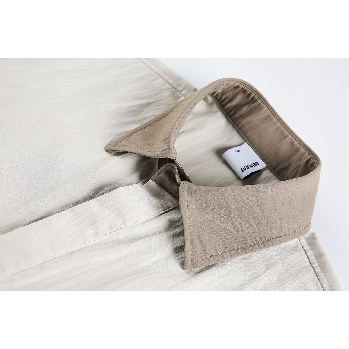 Close-up of a light beige shirt collar, inner seam, and sewn-in neck label.