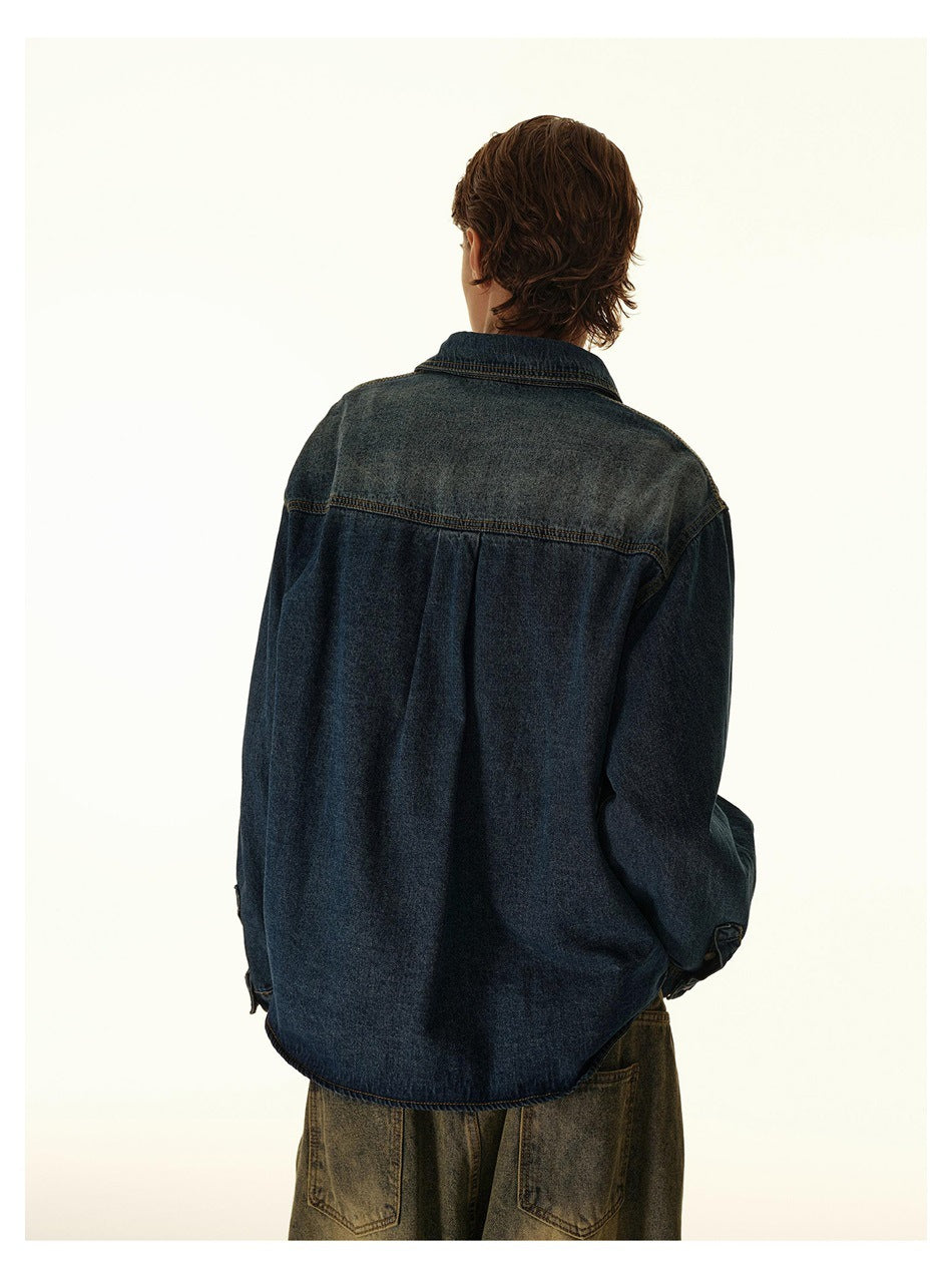 Closer rear view showing the yoke seam and plain back of a dark blue denim overshirt worn by a man.