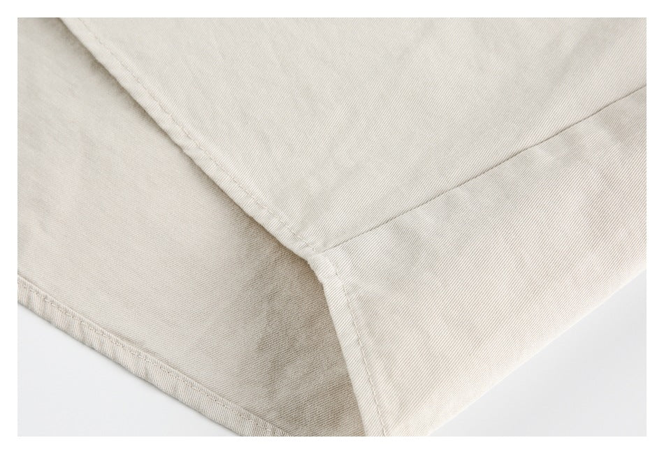 Close-up of a folded light beige garment showing an intersecting stitched seam and finished edge.