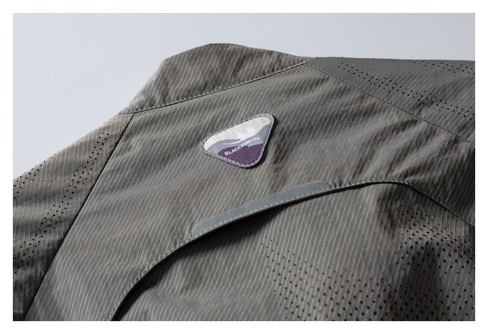 Close-up of gray pinstriped, perforated garment fabric with a small BLACK ARMADA patch.