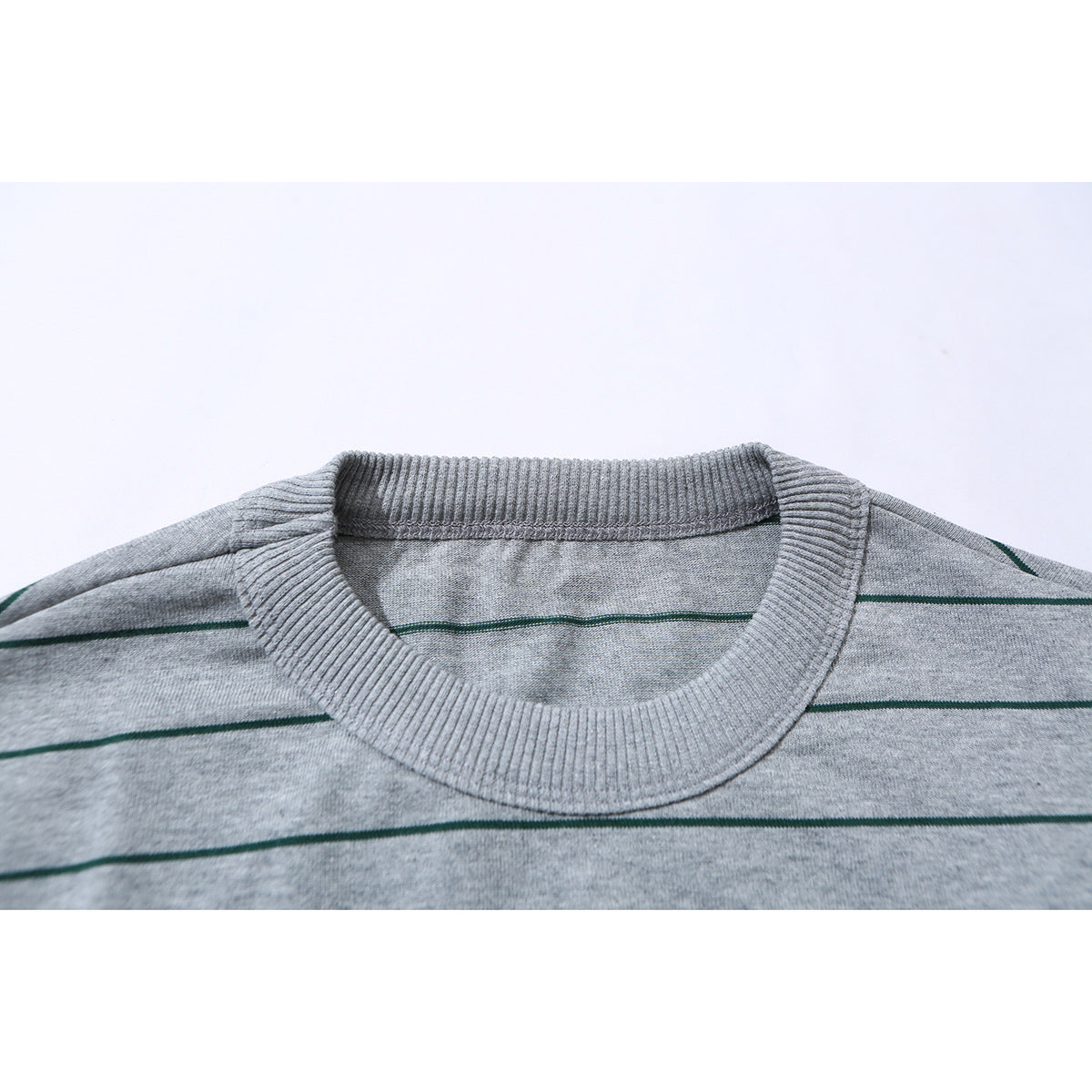 Close-up of a gray T-shirt’s ribbed crew neck and thin dark green stripes.