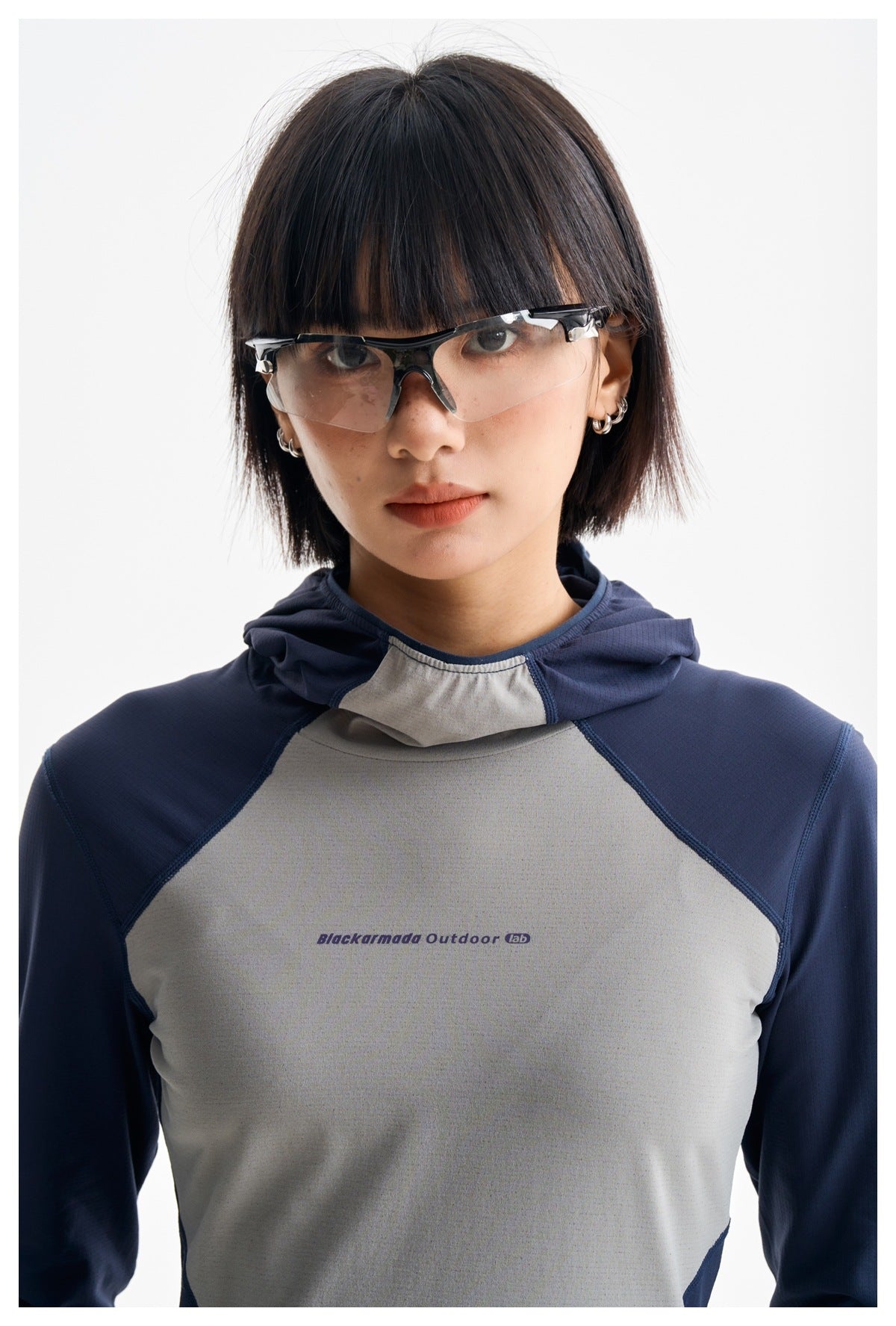 Close-up of a model wearing a navy and gray hooded top with small chest lettering.