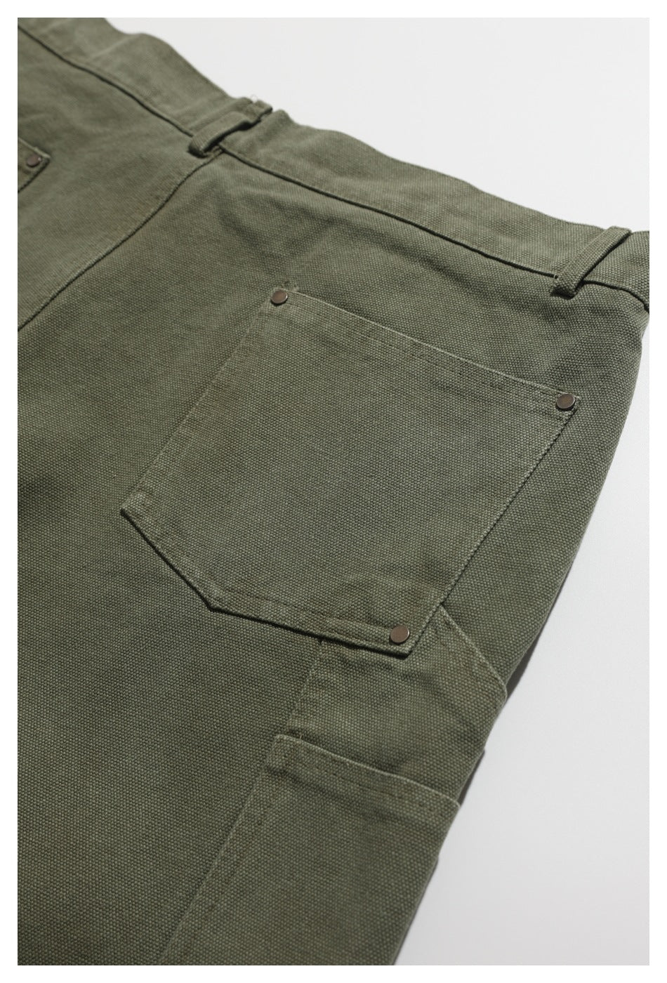Close-up of an olive-green garment pocket with metal rivets, belt loops, and a side seam.