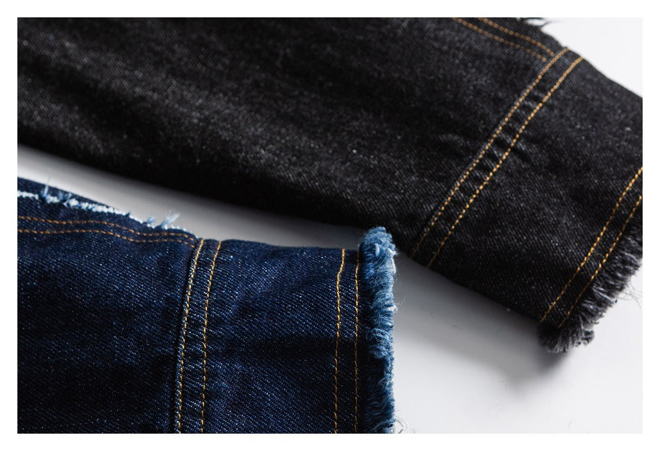 Close-up of black and dark blue denim hems with contrasting gold stitching and frayed edges.