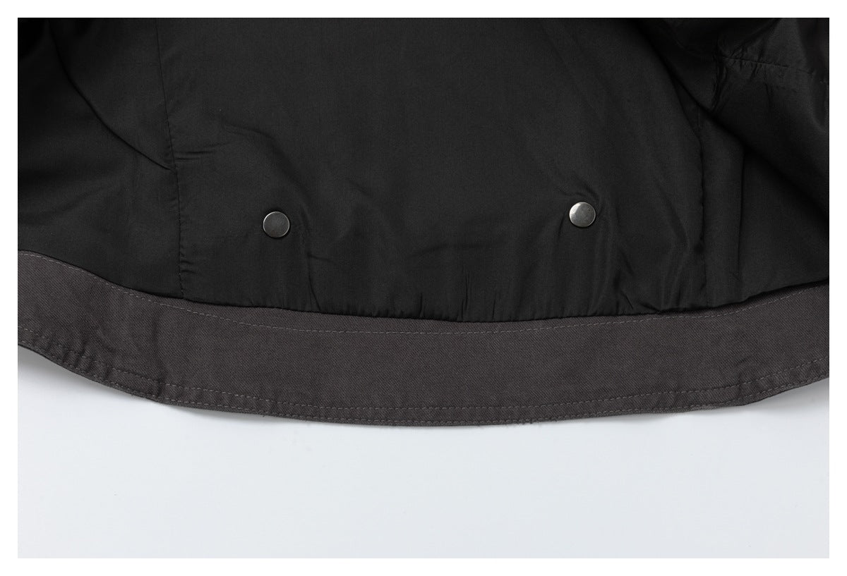 Inside hem of a dark jacket showing black lining, two snap fasteners, and a charcoal outer band.