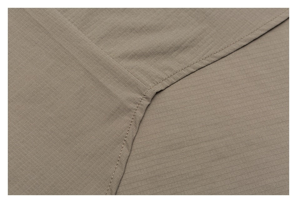Close-up of taupe fabric with a curved stitched seam and subtle grid texture.