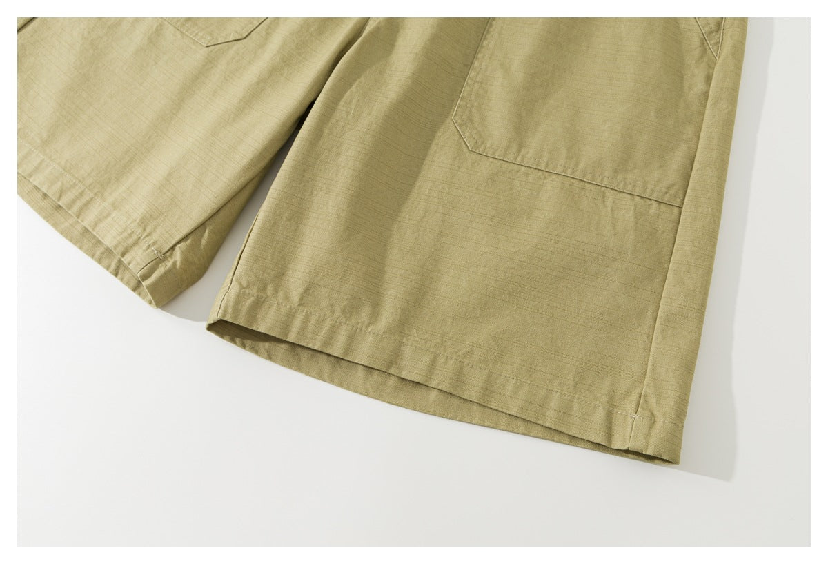 Close-up of the khaki shorts' wide leg hems and lower patch-pocket edges.