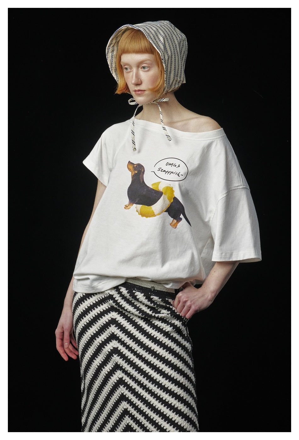 Close view of a model wearing a white dog graphic T-shirt with a black-and-white fringed chevron skirt.