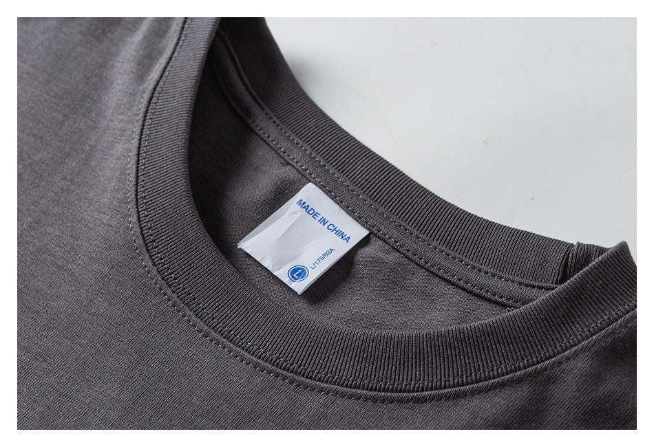 Close-up of a charcoal T-shirt's ribbed crew neck and sewn-in label reading “MADE IN CHINA.”