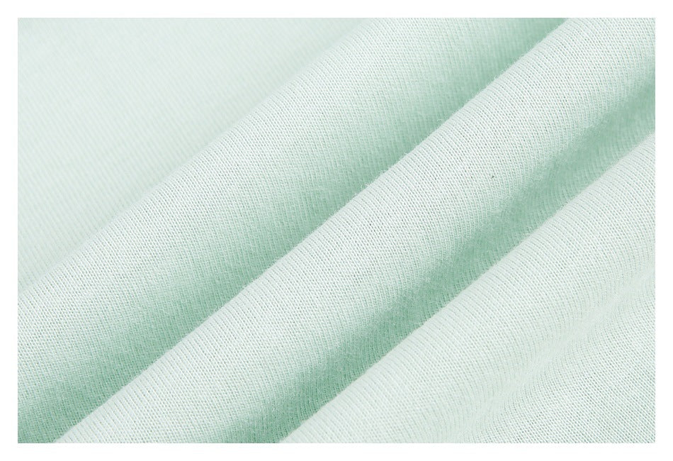 Macro view of pale mint fabric draped in soft folds, showing its fine knit texture.