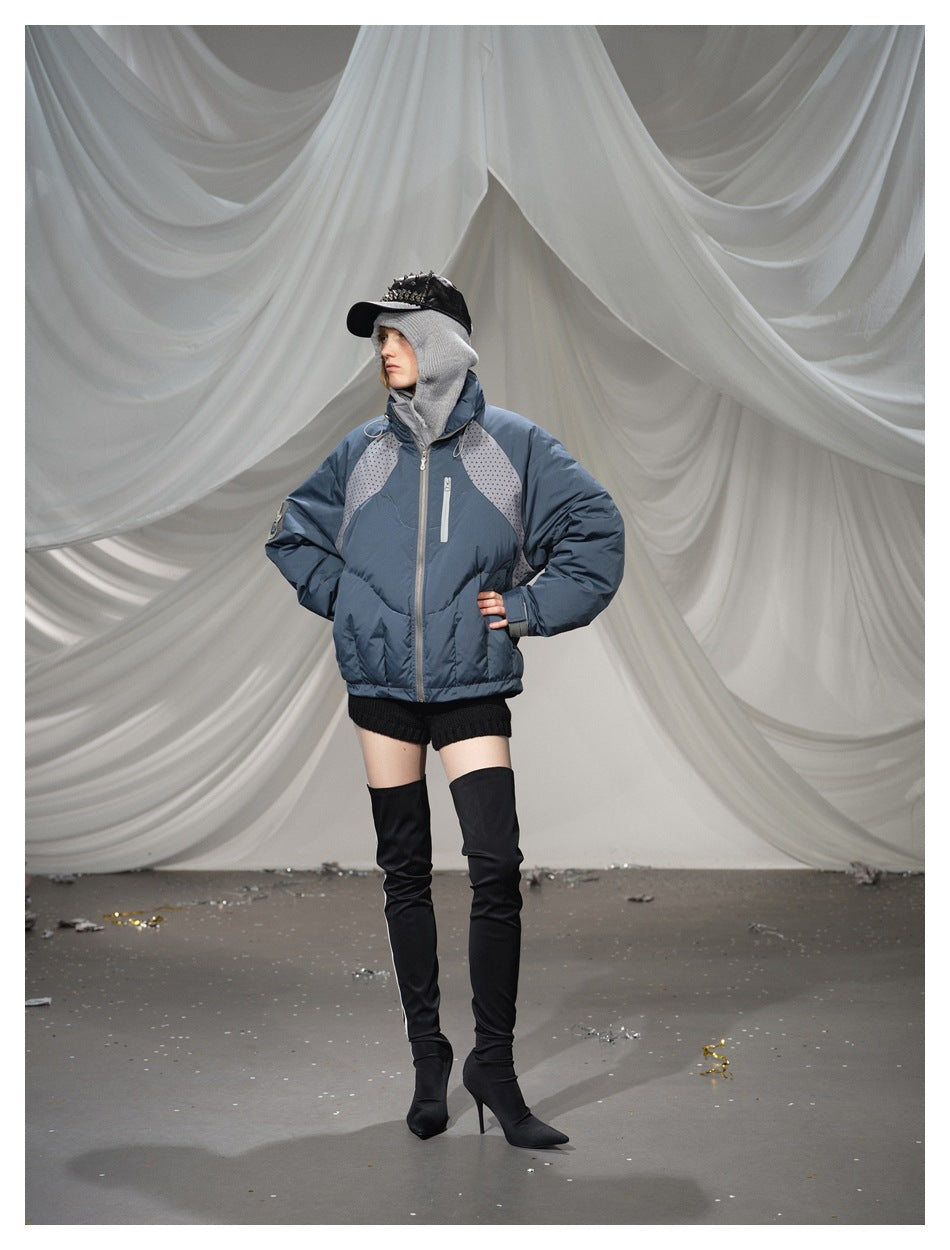 Model wearing a blue-gray puffer jacket with dotted shoulder panels, front zipper, and vertical chest pocket.