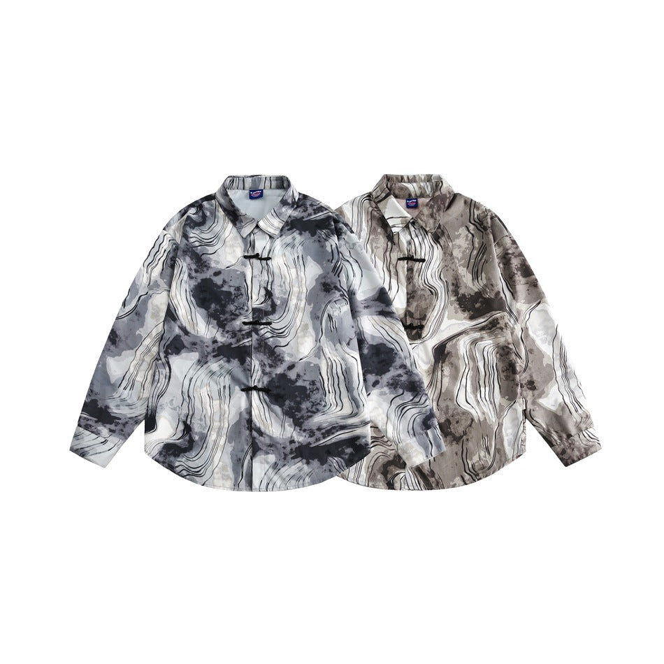 Two flat-laid shirts with black frog closures, one in gray and cream and one in taupe and cream abstract prints.