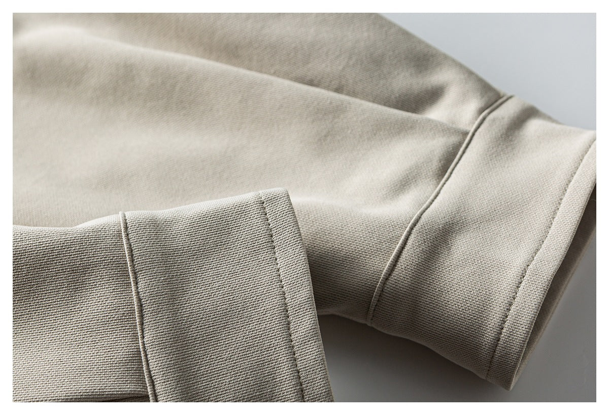 Close-up of a wide cuff and stitched seams on light taupe fabric.