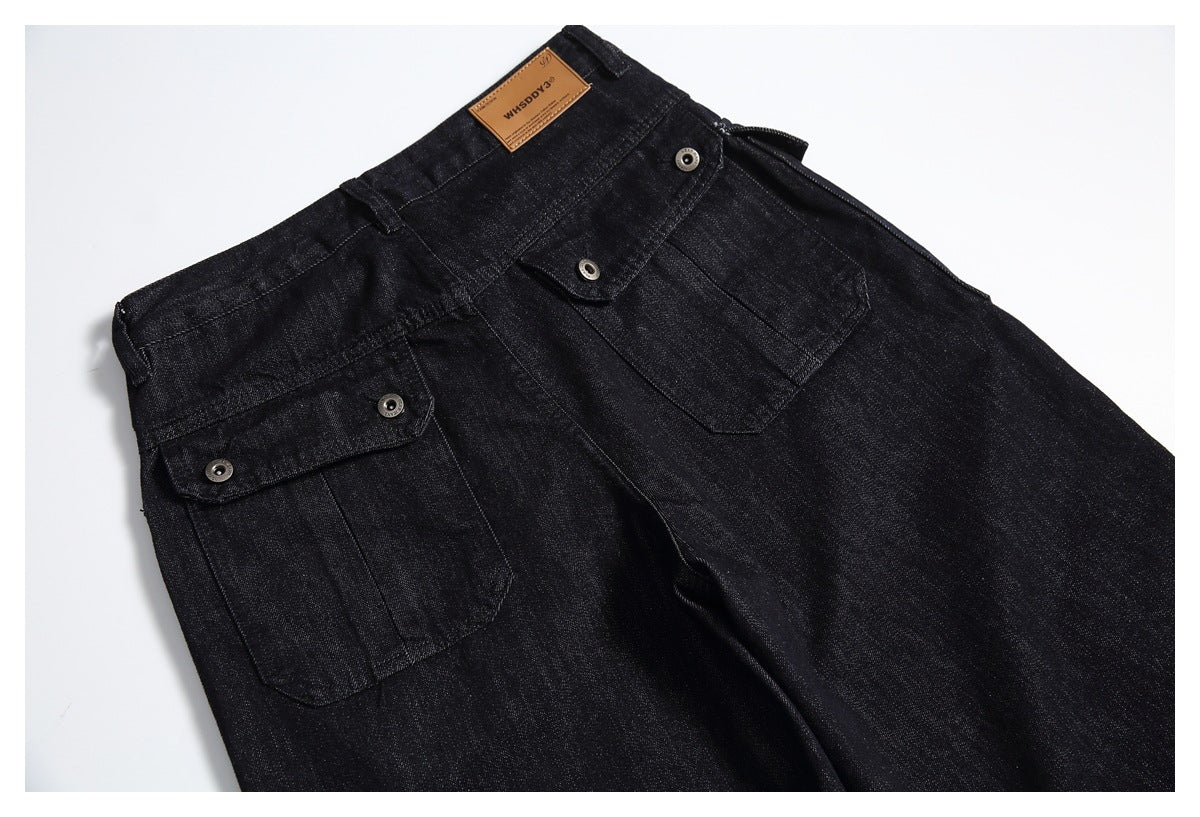 Angled close view of black jeans with large flap pockets and metal snaps.