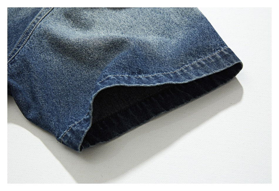 Close-up of a curved finished edge on faded blue denim, showing the dark inner side and stitching.