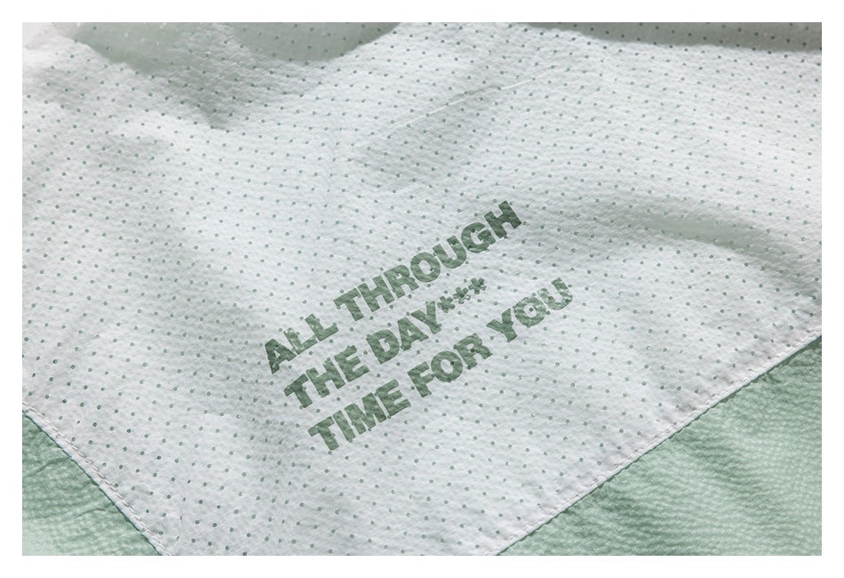 Inside view of mint-green garment lining with dotted white fabric and the printed phrase “ALL THROUGH THE DAY... TIME FOR