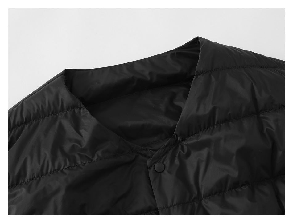 Close-up of a black quilted vest's V-shaped neckline and single black snap closure.