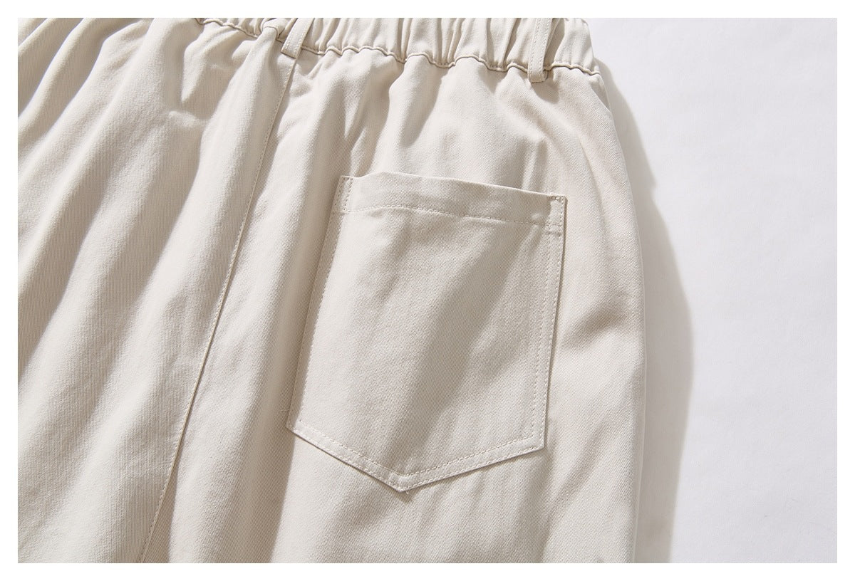 Close-up of the back of cream trousers showing the gathered waistband and a single patch pocket.