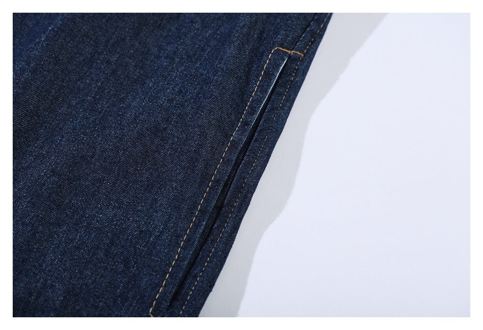 Close-up of dark indigo denim with contrasting tan stitching along a narrow seam.